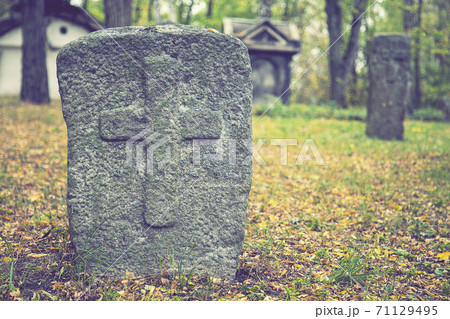A worn sandstone grave marker in the shade on a very bright day. There is no text visible on the stone, but there is some moss on the top. Tombstone and graves in an ancient church graveyard. toned A worn sandstone grave marker in the shade on a very bright day. There is no text visible on the stone, but there is some moss on the top. Tombstone and graves in an ancient church graveyard. toned 71129495