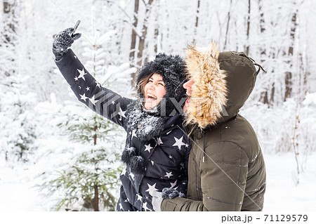 Season and relationship concept - Funny couple taking selfie in the winter time 71129579