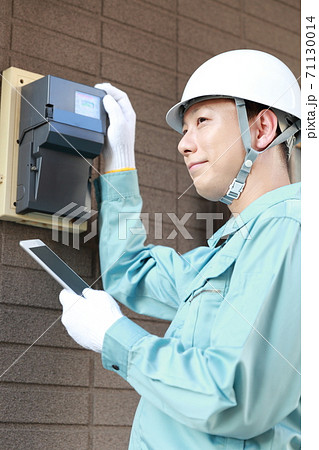 電気メーターをメンテナンスする作業員の男性 71130014