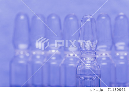 Glass medical ampoule vial for injection. Medicine is liquid sodium chloride with of aqueous solution in ampulla. Close up. Bottles ampule multicolor. 71130041