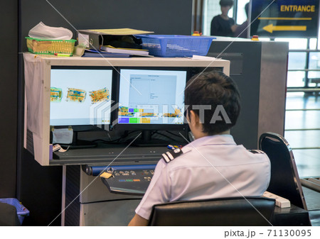 Checking luggage at the airport. A policeman watches a monitor baggage scanner. Checking luggage at the airport. A policeman watches a monitor baggage scanner. 71130095