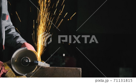Forge workshop. Smithy manual production. Close up details of sparks, industrial worker using angle grinder and cutting steel. 71131815
