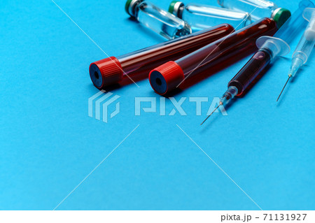 Syringe, test tubes with blood samples and ampoules with medicines or vaccine over blue background 71131927