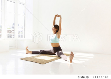 Flexible woman doing yoga at home 71133248