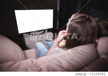 Young family of a man and a woman are lying on the sofa and watching TV. The TV screen is clipped in white. Mockup and template for design layout 71133431