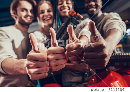 Group of young friends giving thumbs up in arcade. 71135044