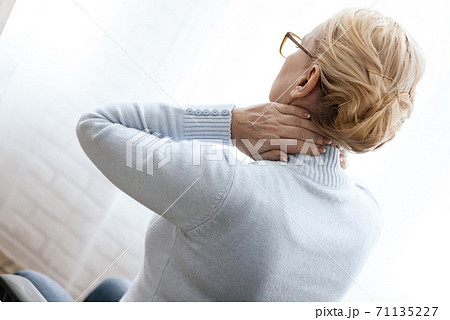 Woman doing hand massage for sore neck. 71135227