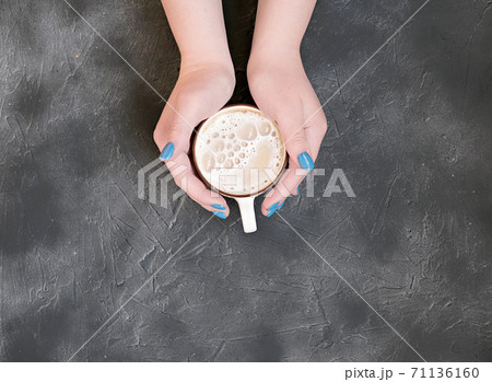 womans hands with blue manicure holding a cup of hot coffee womans hands with blue manicure holding a cup of hot coffee 71136160