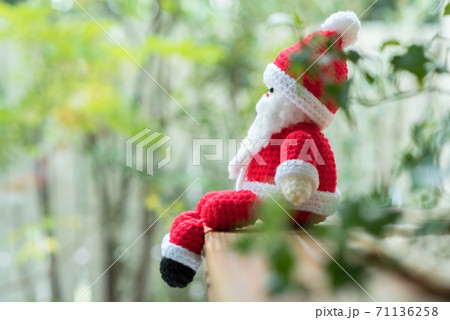 窓辺の家具に座るサンタクロースの編みぐるみ 71136258