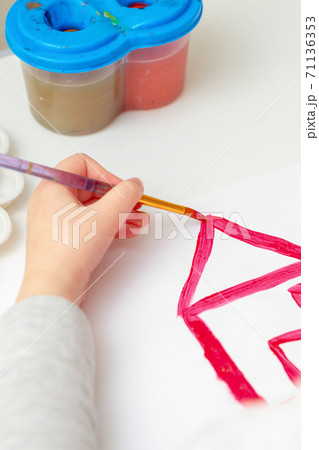 Child's hand drawing the house. 71136353