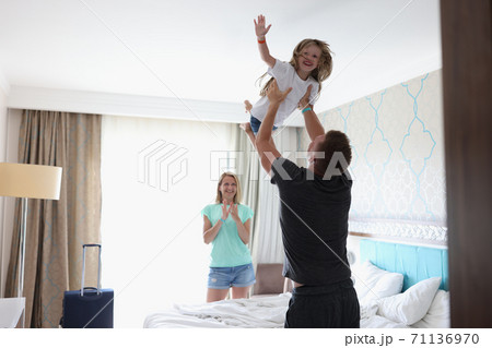 Man tosses laughing child over his head in bedroom. Man tosses laughing child over his head in bedroom. 71136970