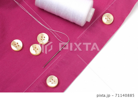 Coil with white threads and a needle and sewn pearl buttons on the shirt Coil with white threads and a needle and sewn pearl buttons on the shirt 71140885