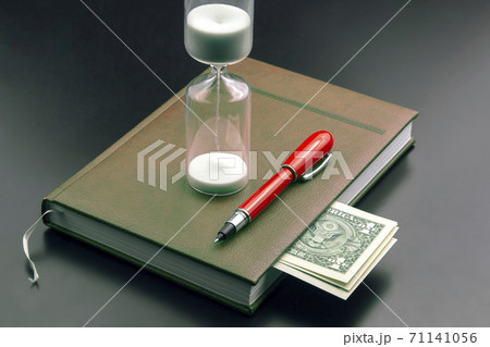 Hourglass, money, pen and notebook are on the table. Business office items. Time is money.  Hourglass, money, pen and notebook are on the table. Business office items. Time is money.  71141056
