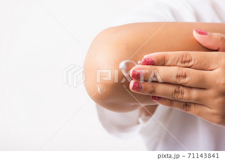 Woman applies lotion cream on her elbow Woman applies lotion cream on her elbow 71143841