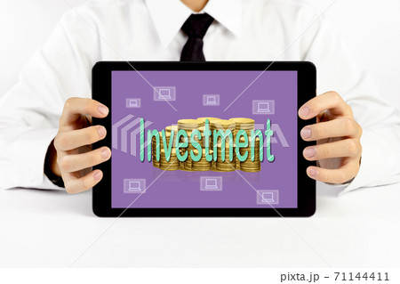 Businessman holding a tablet with green word Investment and golden coins stacks and laptop icons 71144411
