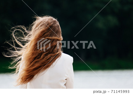 Woman standing looking at the lake. The hair was blown away by the wind. Woman standing looking at the lake. The hair was blown away by the wind. 71145993