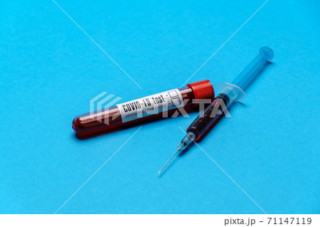 Syringe And Plastic Test Tube With Blood Sample over blue background with copyspace 71147119