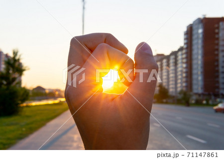 human hand covers the sunlight, the sun shines through the hand. urban landscape. selective focus human hand covers the sunlight, the sun shines through the hand. urban landscape. selective focus 71147861