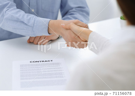 Business people shaking hands at meeting or negotiation after contract discussing. Businessman and woman handshake at office while sitting at the desk. Success concept Business people shaking hands at meeting or negotiation after contract discussing. Businessman and woman handshake at office while sitting at the desk. Success concept 71156078