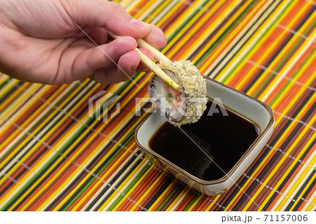 Sushi roll with salmon warm in tempura held in bamboo sticks over soy sauce Sushi roll with salmon warm in tempura held in bamboo sticks over soy sauce 71157006