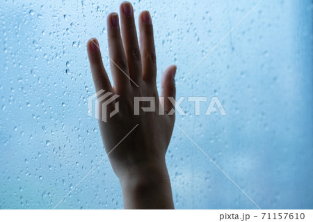 Female hand at the window during the rain. Glass in drops of water. 71157610