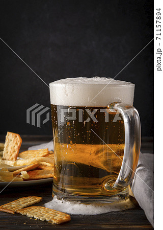 mug of light beer with foam and cracker on a dark background mug of light beer with foam and cracker on a dark background 71157894