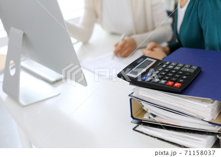 Calculator and binders with papers are waiting to be processed by business woman or bookkeeper working at the desk in office back in blur. Internal Audit and tax concept 71158037