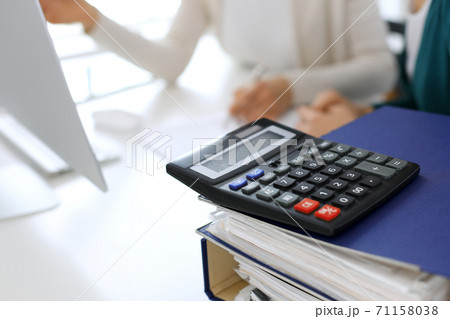 Calculator and binders with papers are waiting to be processed by business woman or bookkeeper working at the desk in office back in blur. Internal Audit and tax concept Calculator and binders with papers are waiting to be processed by business woman or bookkeeper working at the desk in office back in blur. Internal Audit and tax concept 71158038