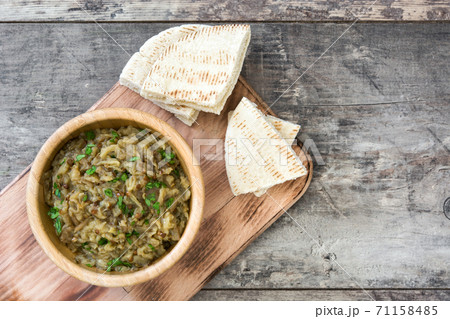 Baba ganoush in wooden bowl and pita bread on wooden table. Top view Baba ganoush in wooden bowl and pita bread on wooden table. Top view 71158485
