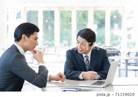 セールスをするミドルエイジの男性とそれを聞く若い男性 セールスをするミドルエイジの男性とそれを聞く若い男性 71159020