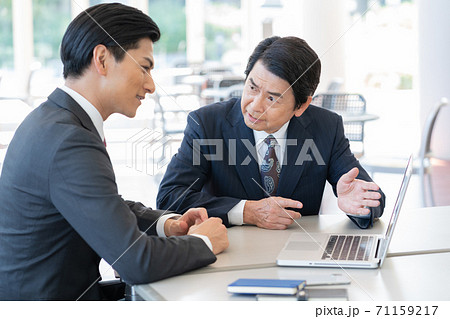 セールスをするミドルエイジの男性とそれを聞く若い男性 セールスをするミドルエイジの男性とそれを聞く若い男性 71159217