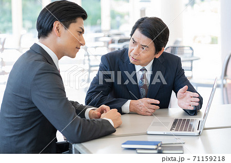 セールスをするミドルエイジの男性とそれを聞く若い男性 71159218