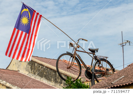 The Malaysia National Flag hangs on a rod mounted on the roof with an old retro bicycle, Penang. 71159477