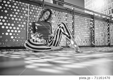 Black and white photo of a woman on a sunny balcony Black and white photo of a woman on a sunny balcony 71161470