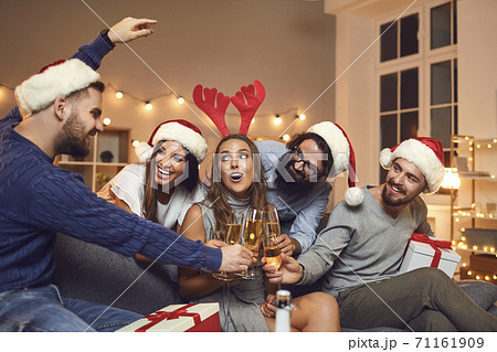Happy friends in holiday hats having fun during Christmas celebration party at home with champagne 71161909