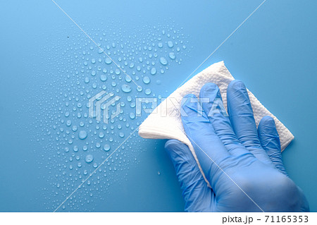 hand in blue rubber gloves cleaning table with cloth  71165353