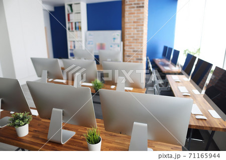 Many silver monitors stand on a wooden table in office closeup 71165944