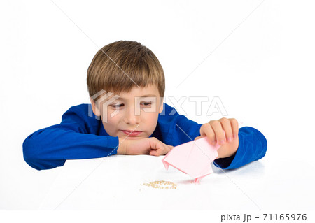 Origami: a schoolboy boy in a blue T-shirt sits at the table and plays with a paper bird, wants to feed her 71165976