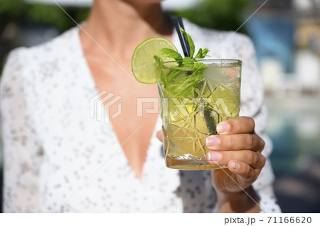 Woman in white dress drinking a mojito cocktail 71166620