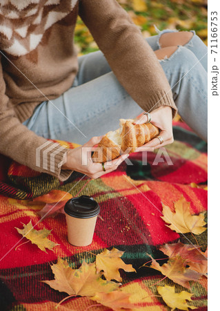 Cozy picnic with croissant, cup of coffee and autumn leafs on plaid blanket. 71166753