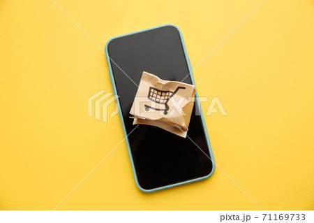 Damaged paper box on a smartphone's screen isolated on yellow background. Online shopping, service and delivery concept 71169733