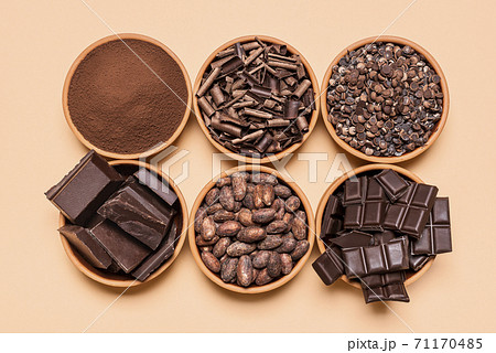 Chocolate pieces and cacao beans in bowls. Chocolate ingredient isolated on yellow background Chocolate pieces and cacao beans in bowls. Chocolate ingredient isolated on yellow background 71170485