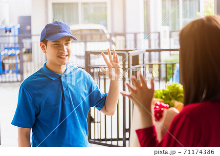 Delivery man making grocery service giving fresh vegetables in paper bag to woman customer 71174386