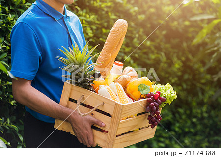Man farmer wears delivery uniform he holding full fresh vegetables and fruits in crate wood box 71174388