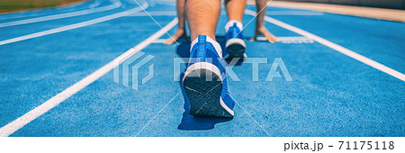 Sprinter fit man waiting for start of race on running tracks at outdoor stadium. Sport and fitness runner athlete on blue run track starting line with running shoes. Banner panorama Sprinter fit man waiting for start of race on running tracks at outdoor stadium. Sport and fitness runner athlete on blue run track starting line with running shoes. Banner panorama 71175118
