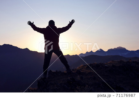 tourist with arms raised standing on the mountain at dawn tourist with arms raised standing on the mountain at dawn 71176987