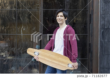 スケボーを持つ若い男性 71182677