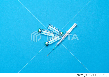 Syringe and ampoules with medicines or vaccine over blue background 71183630