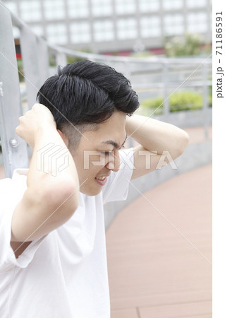 頭をかかえる若い男性 71186591