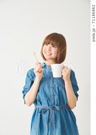 ハブラシとカップを持つ若い女性 71186862